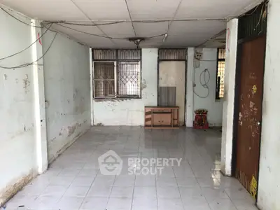 Spacious empty room with tiled floor and large windows, ideal for renovation.