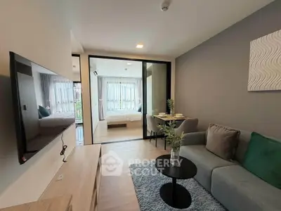 Modern living room with open layout leading to a cozy bedroom, featuring stylish decor and natural light.