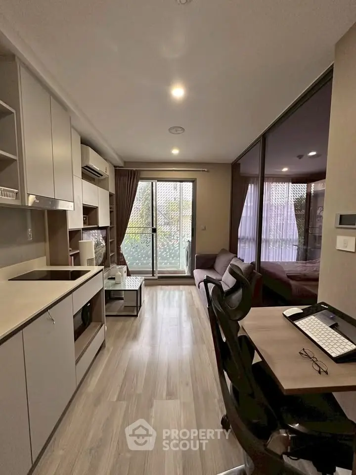 Modern studio apartment with open layout and balcony view, featuring sleek kitchen and cozy living area.