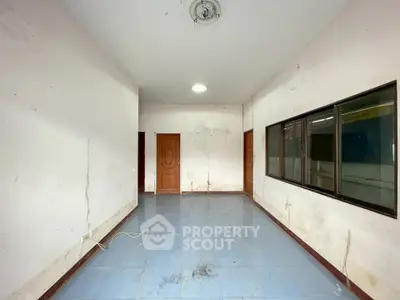 Spacious empty room with tiled floor and large window, ideal for customization.