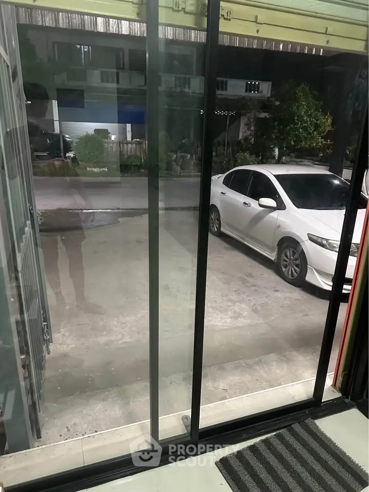 Modern home entrance with sliding glass doors and driveway view.