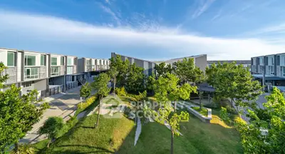 Modern townhouse complex with lush green landscaping and clear blue sky.