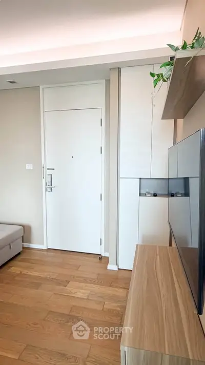Modern living room with wooden flooring and sleek TV setup, featuring a cozy sofa and stylish decor.