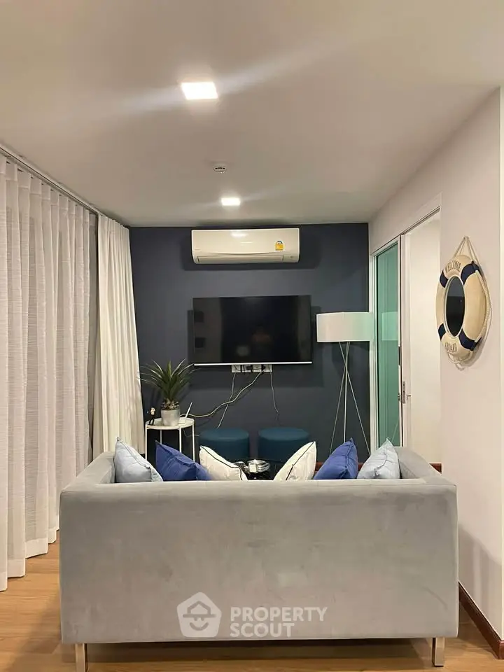 Modern living room with sleek gray sofa, wall-mounted TV, and stylish decor.