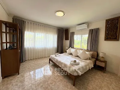 Spacious bedroom with elegant decor and large windows offering natural light.
