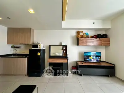 Modern studio apartment with sleek kitchen and entertainment area, featuring stylish cabinetry and contemporary decor.