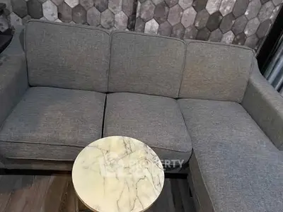 Stylish gray sectional sofa with marble side table in modern living room.