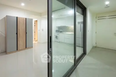 Modern apartment with sleek kitchen and laundry area, featuring sliding glass doors and ample storage.