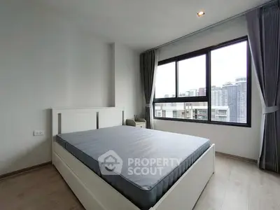 Spacious bedroom with large window offering city view, modern design and ample natural light.