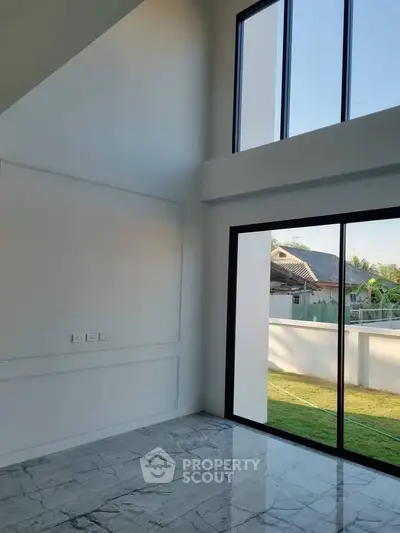 Spacious modern living room with high ceilings and large windows offering natural light and garden view.