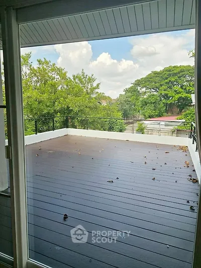 Spacious balcony with scenic view of lush greenery and clear skies.