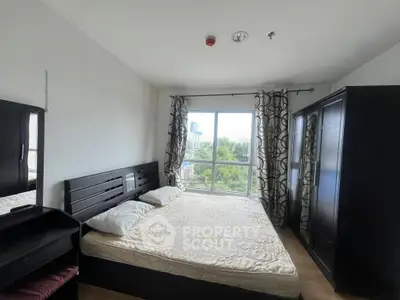 Spacious bedroom with large window and modern furnishings, offering a serene view.