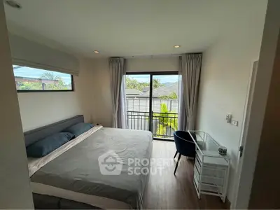 Cozy bedroom with balcony view, featuring a comfortable bed and a small desk, perfect for relaxation and work.