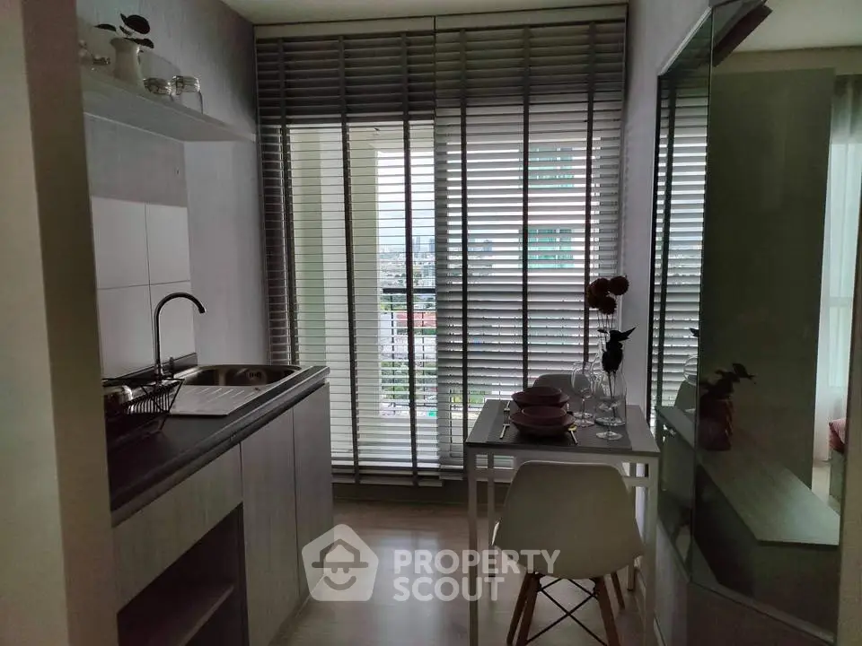 Chic modern kitchen with city view, featuring sleek cabinetry and cozy dining area.