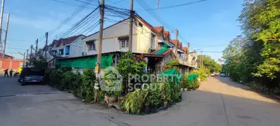 Charming corner townhouse with lush greenery and vibrant neighborhood view.