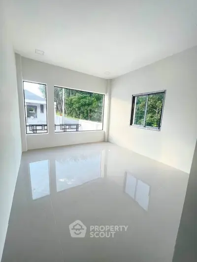 Spacious empty room with large windows offering natural light and serene views, perfect for customization.