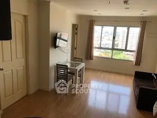 Bright living room with city view, wooden flooring, and wall-mounted TV.