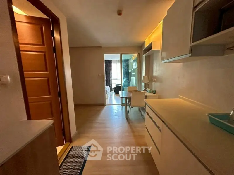 Cozy apartment interior with modern kitchen and dining area, featuring warm lighting and wooden flooring.