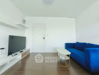 Modern living room with blue sofa and flat-screen TV on wooden floor