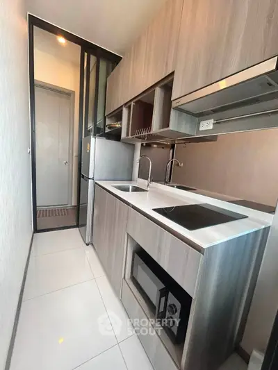 Modern compact kitchen with sleek cabinetry and built-in appliances in a stylish apartment.
