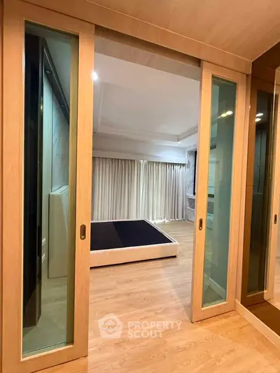 Spacious bedroom with sliding glass doors and wooden flooring in modern apartment.