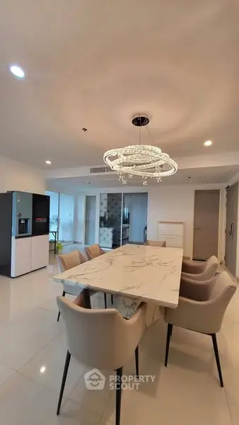 Elegant dining area with modern chandelier and marble table in spacious apartment.