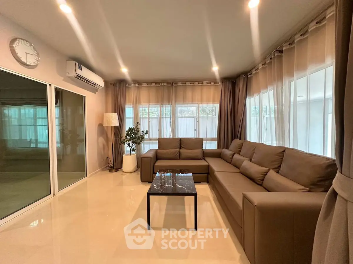 Spacious living room with modern brown sectional sofa and large windows for natural light.