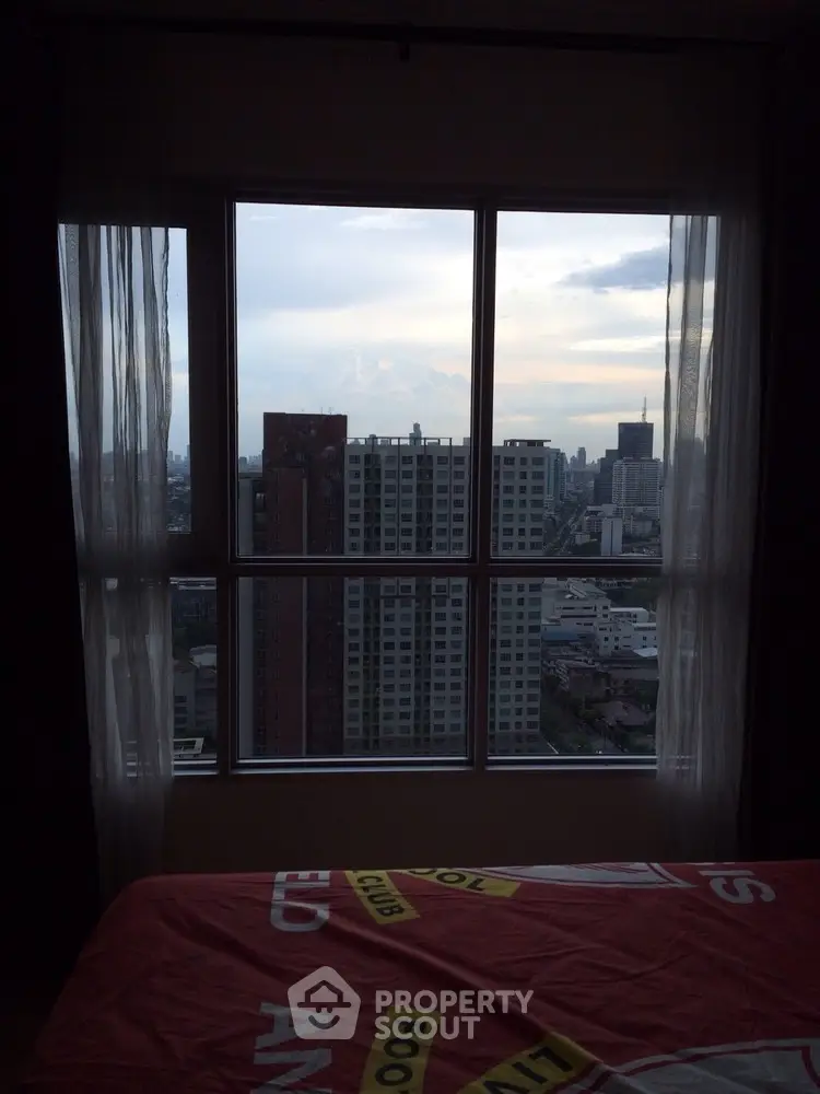Stunning cityscape view from a high-rise apartment bedroom window at dusk.