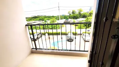 Charming balcony with scenic view of lush greenery and parked cars, perfect for relaxation.