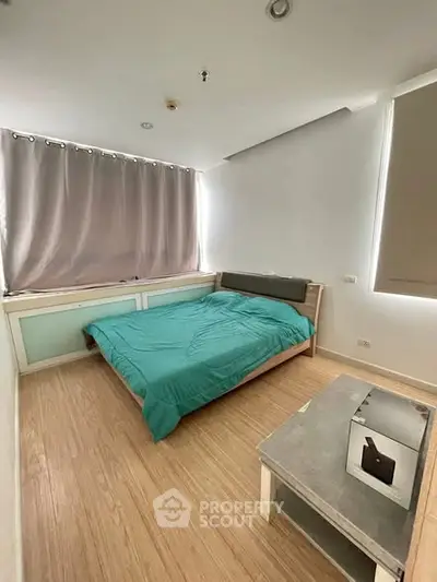 Cozy bedroom with modern design and natural light, featuring a comfortable bed and stylish decor.