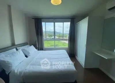 Bright bedroom with large window offering scenic views, featuring a cozy bed and modern wardrobe.