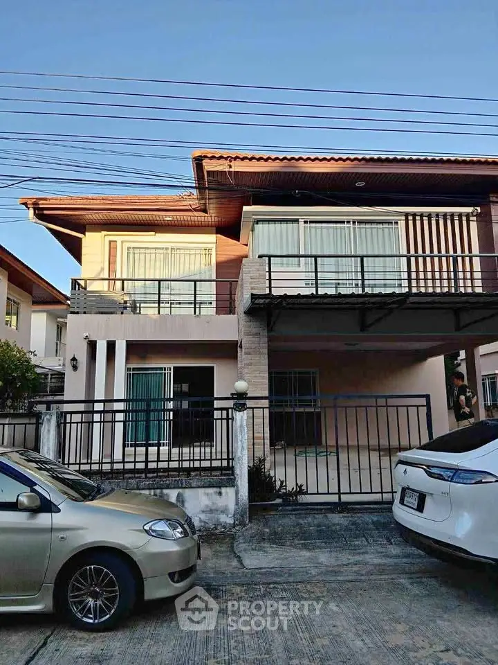 Charming two-story house with spacious balcony and gated driveway in a serene neighborhood.