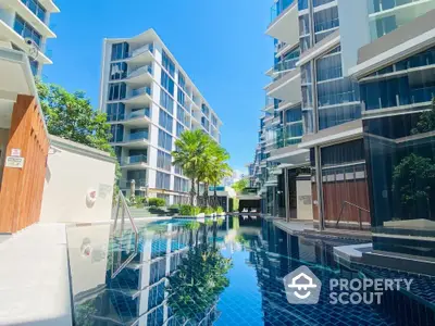 Luxurious modern apartment complex with stunning pool and sleek architecture under clear blue sky.