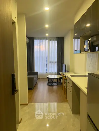 Modern apartment interior with open kitchen and cozy living room, featuring stylish furniture and natural light.
