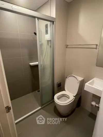 Modern bathroom with glass shower enclosure and sleek fixtures in a contemporary apartment.