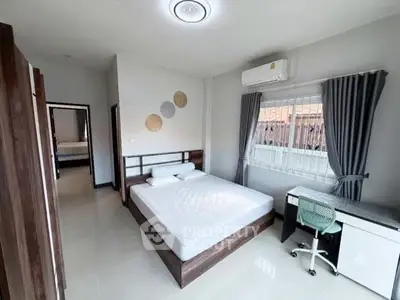 Spacious bedroom with modern decor and natural light, featuring a comfortable bed and study desk.