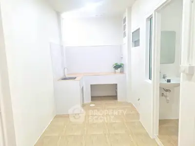 Minimalist kitchen with wooden flooring and white walls, featuring a compact sink and countertop.