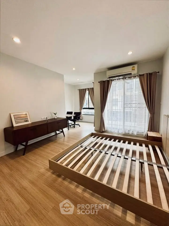 Spacious bedroom with wooden flooring and large windows in modern apartment