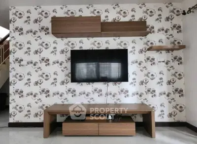 Stylish living room with modern TV setup and floral wallpaper accent wall.