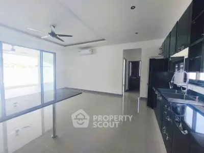 Spacious modern kitchen with sleek black cabinetry and open layout, featuring ceiling fan and large sliding doors.