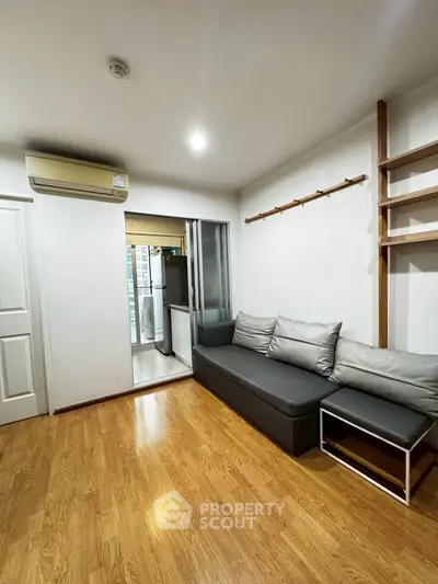 Modern living room with wooden flooring and sleek gray sofa, featuring a minimalist design.