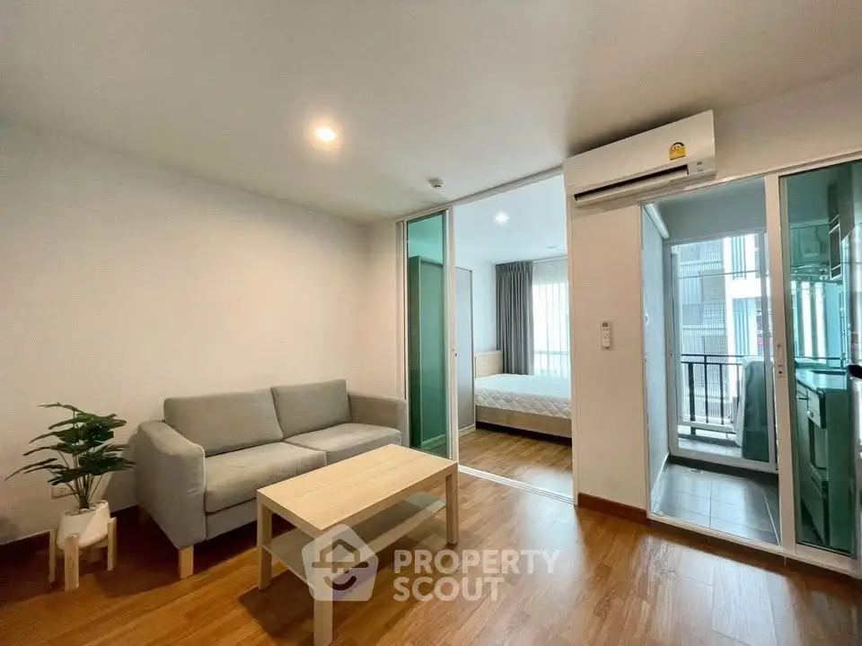 Modern apartment interior with cozy living room and bedroom, featuring wooden flooring and natural light.