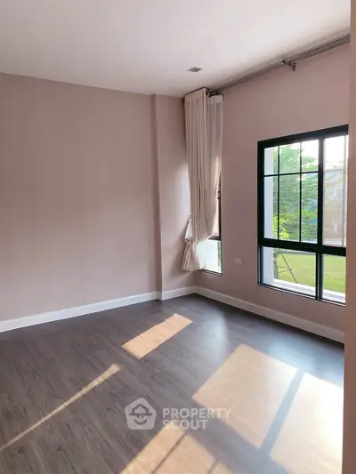 Spacious sunlit room with large windows and elegant curtains, perfect for modern living.