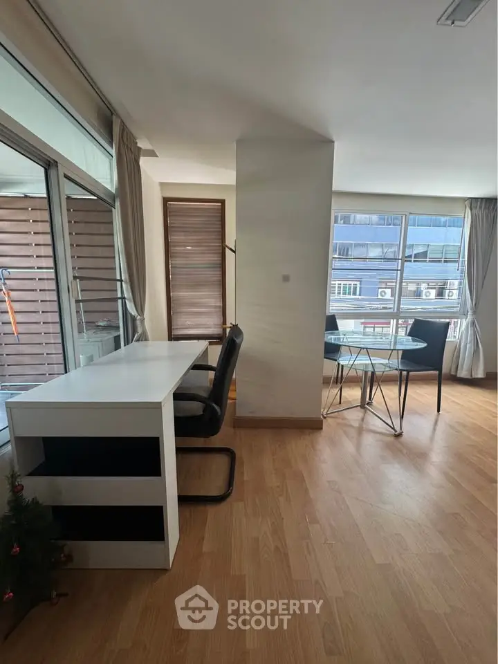 Spacious modern living area with wooden flooring and large windows for natural light.