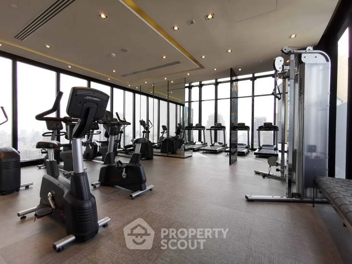 Modern gym with city view, featuring state-of-the-art exercise equipment and floor-to-ceiling windows.