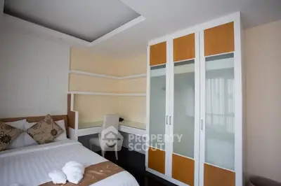 Modern bedroom with built-in desk and wardrobe, featuring neutral tones and cozy bedding.