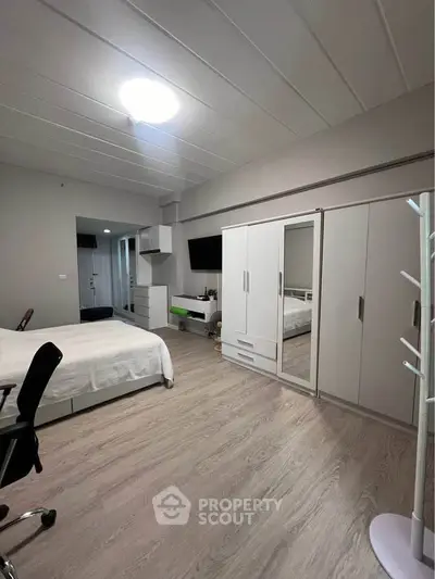 Spacious modern bedroom with sleek furniture and ample storage space.