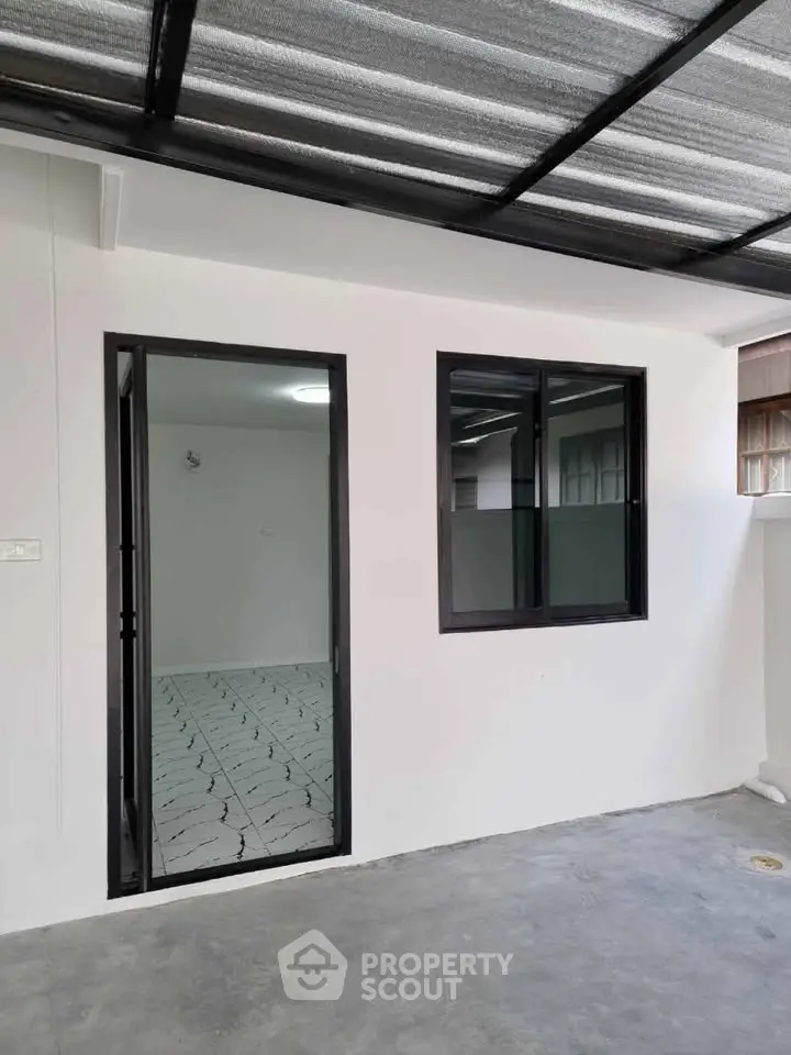Modern exterior with sleek black-framed windows and door, featuring a covered patio area.