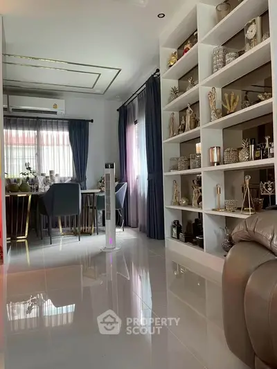 Elegant living room with modern decor and built-in shelving, featuring a dining area and large windows.