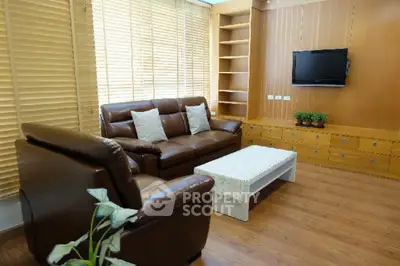 Cozy living room with leather sofas, wooden blinds, and wall-mounted TV, perfect for relaxation.